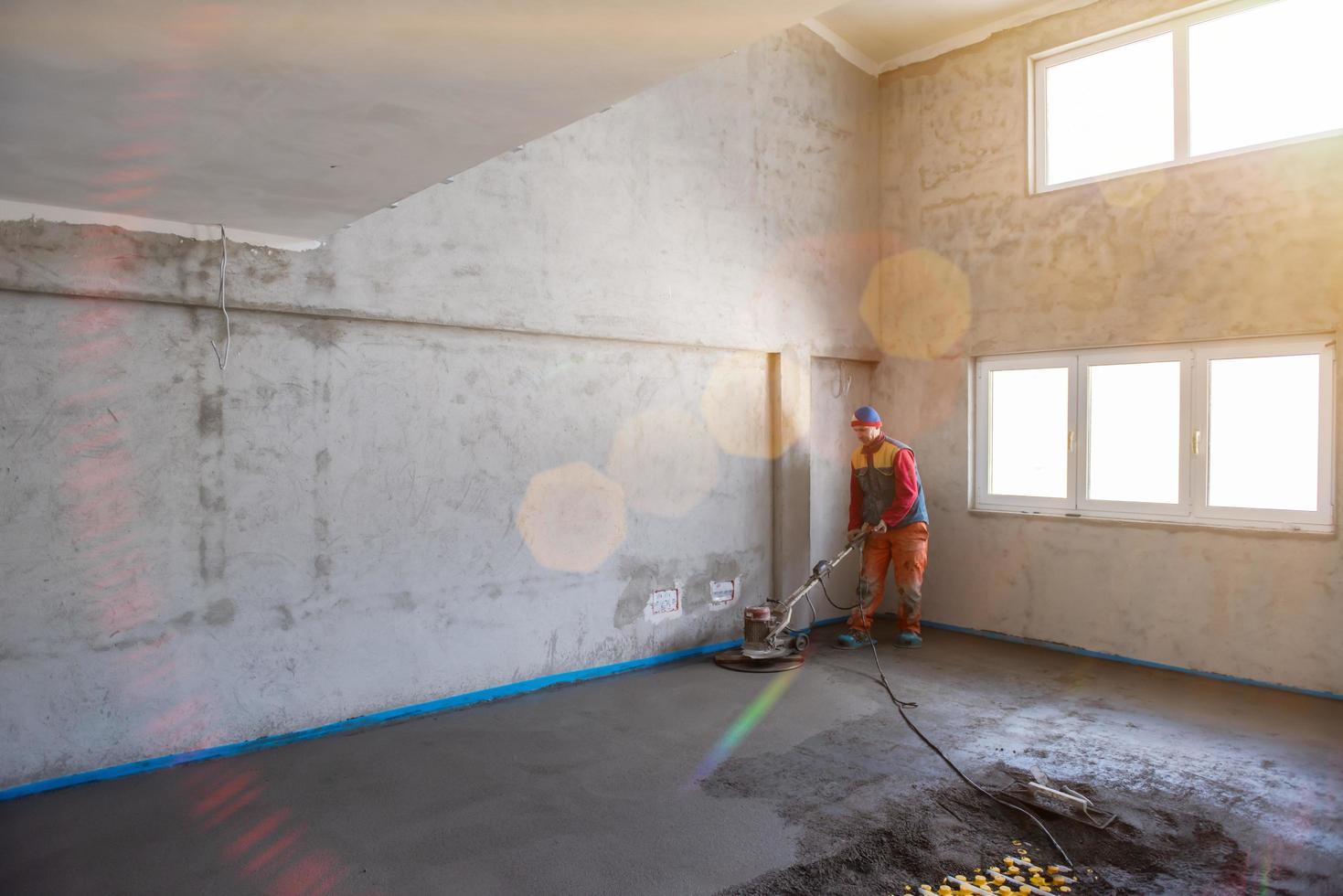 worker performing and polishing sand and cement screed floor photo