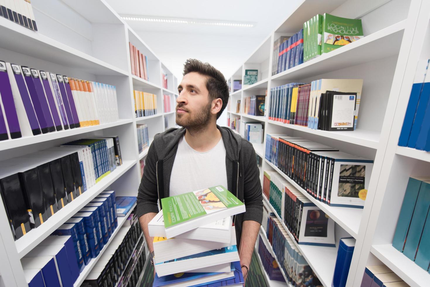 Student holding lot of books in school library photo