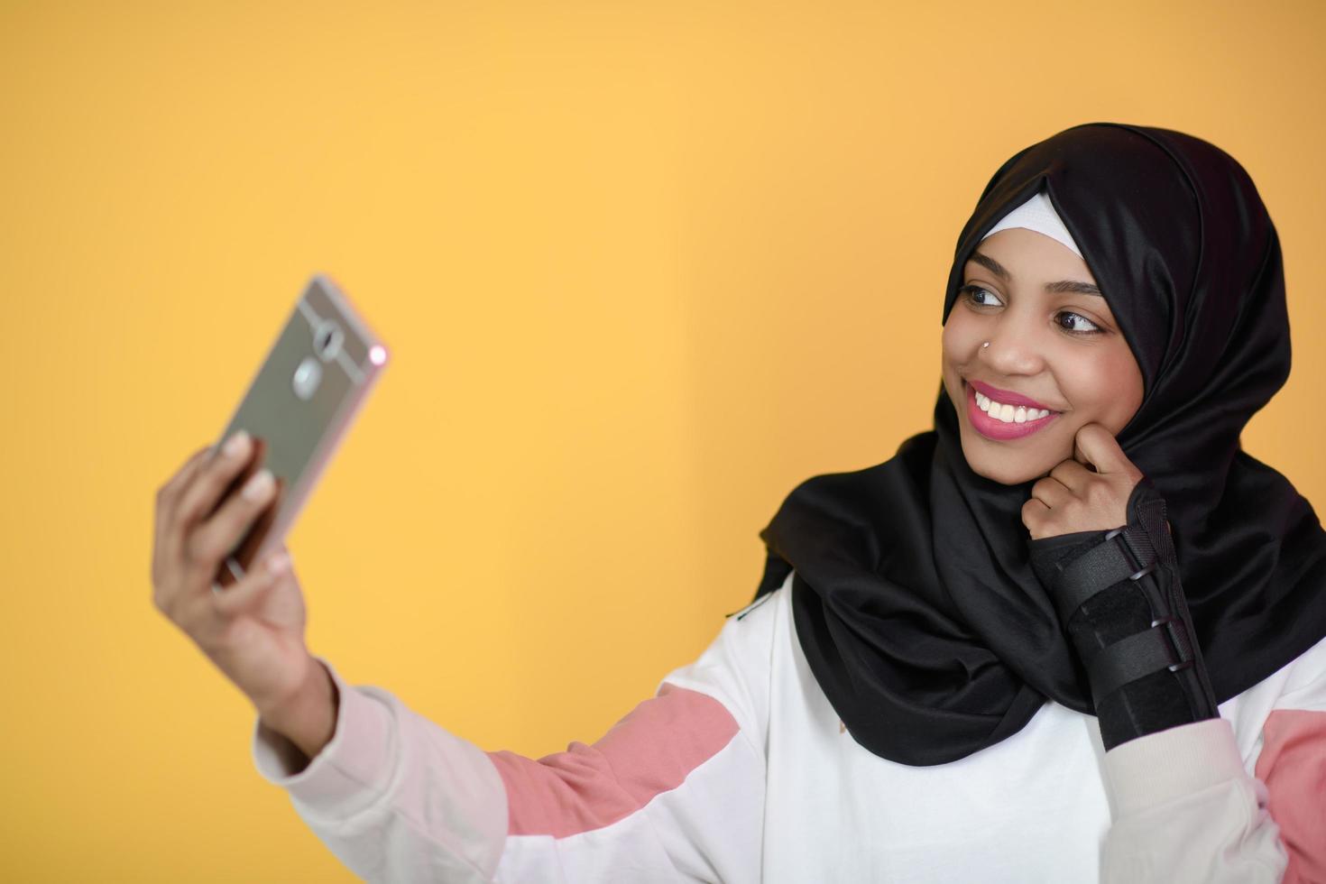 mujer musulmana africana con una hermosa sonrisa se toma un selfie con un teléfono celular foto