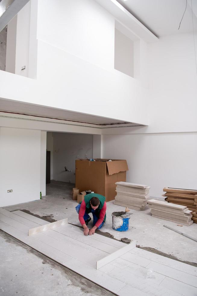 worker installing the ceramic wood effect tiles on the floor photo