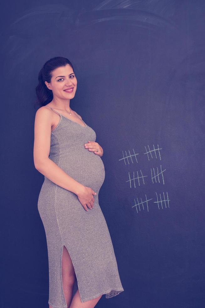 Portrait of pregnant woman in front of black chalkboard photo