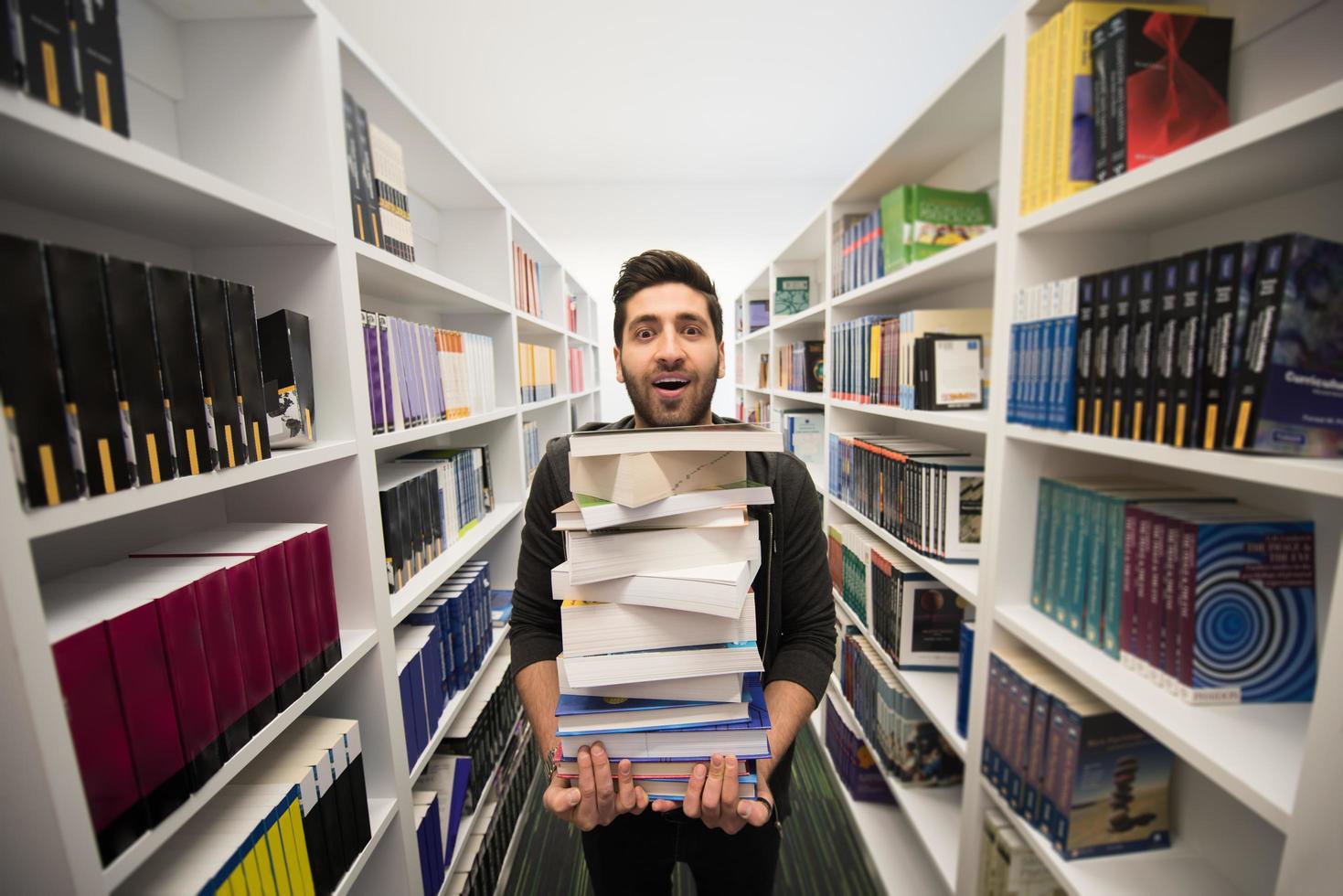 Student holding lot of books in school library photo