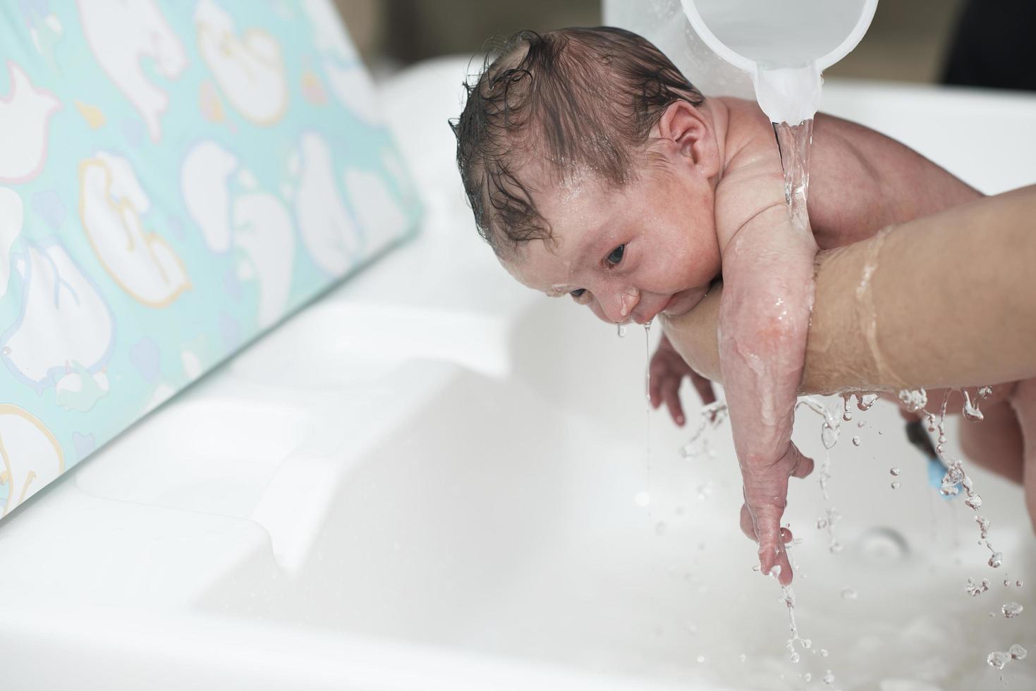 Newborn baby girl taking a first bath photo