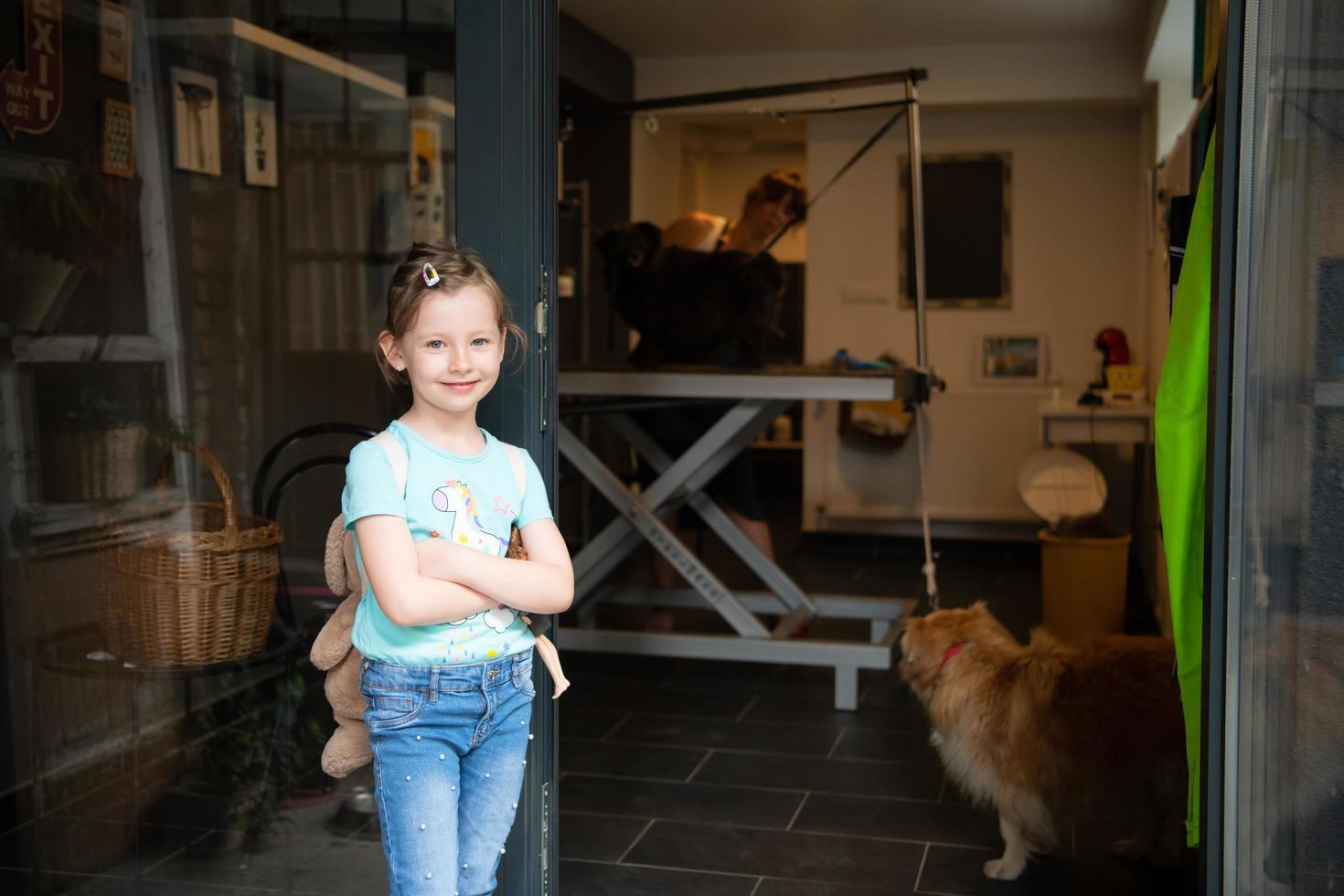 niña linda parada frente al salón de belleza para animales foto