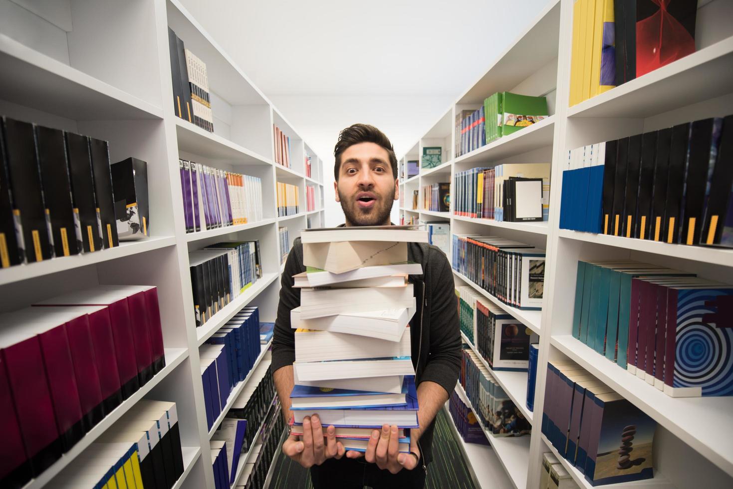 Student holding lot of books in school library photo