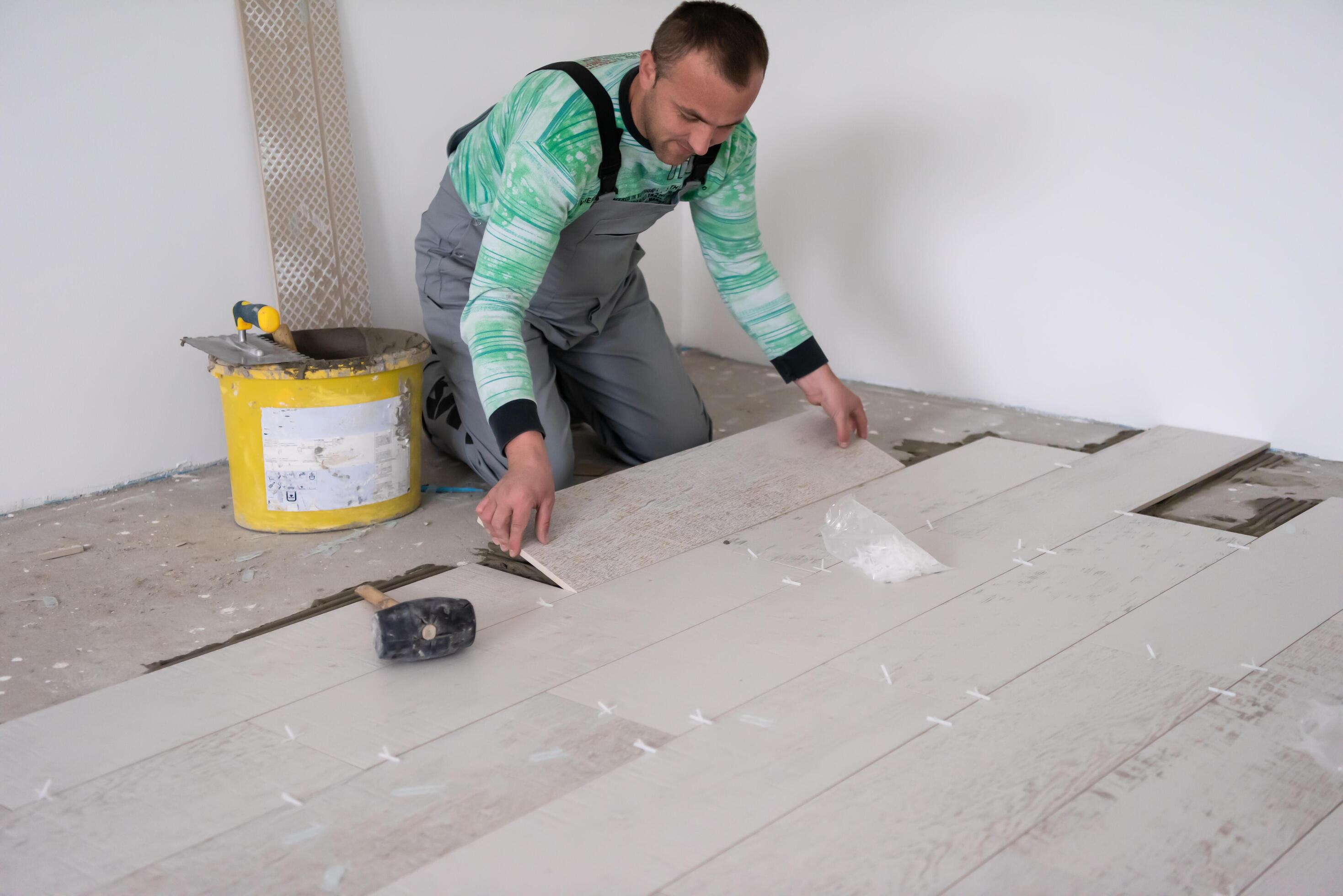 worker installing the ceramic wood effect tiles on the floor 11921024