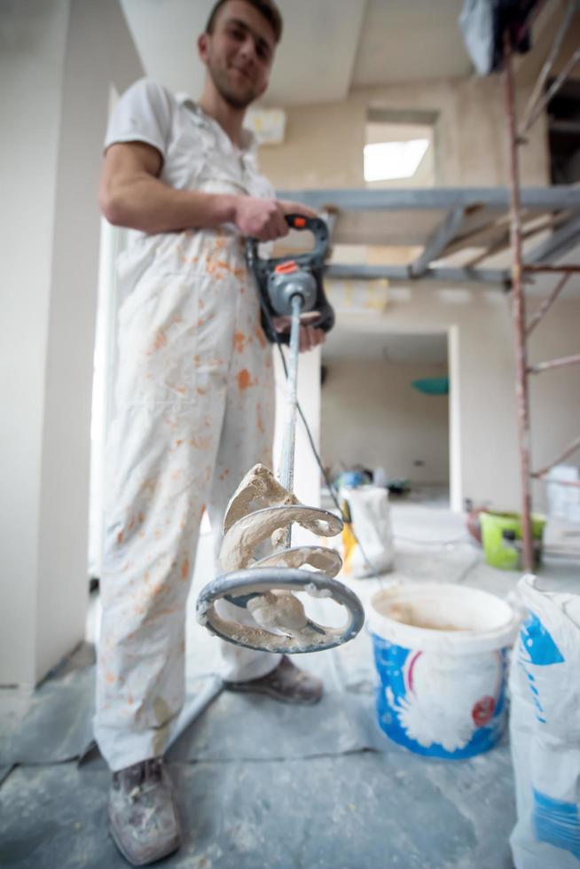 construction worker mixing plaster in bucket photo