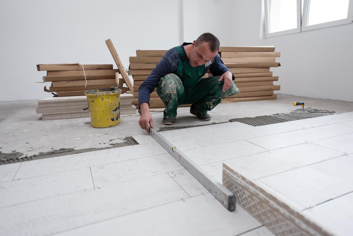 worker installing the ceramic wood effect tiles on the floor photo