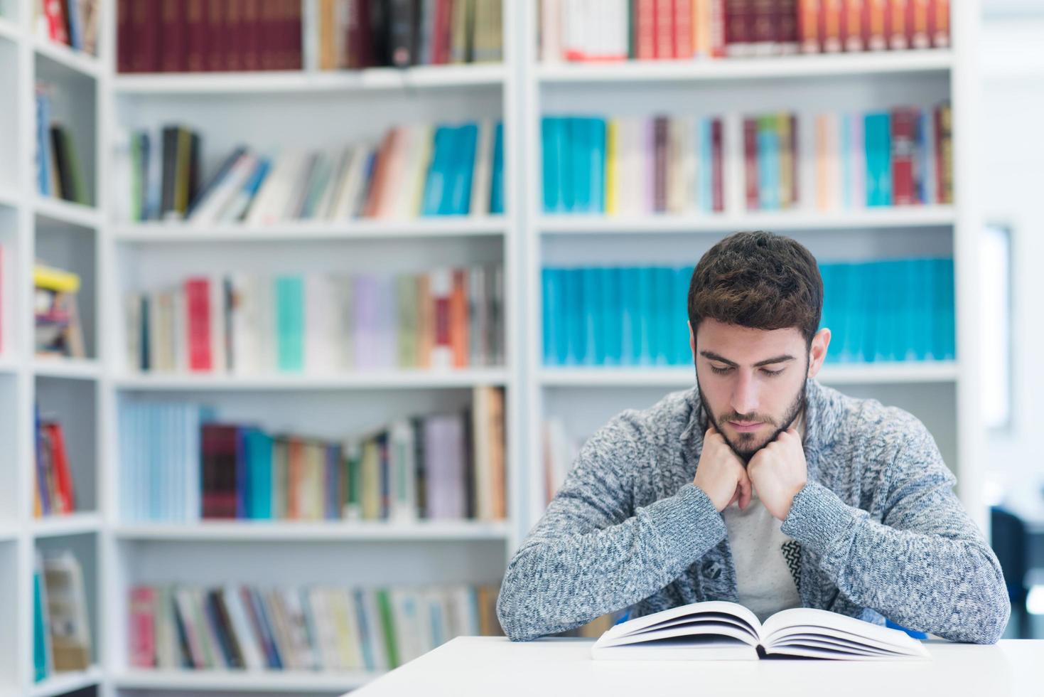 portrait of student while reading book  in school library photo