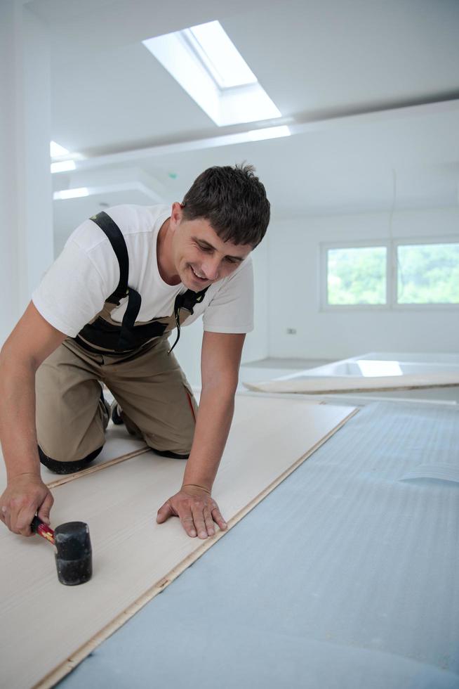 Professional Worker Installing New Laminated Wooden Floor photo