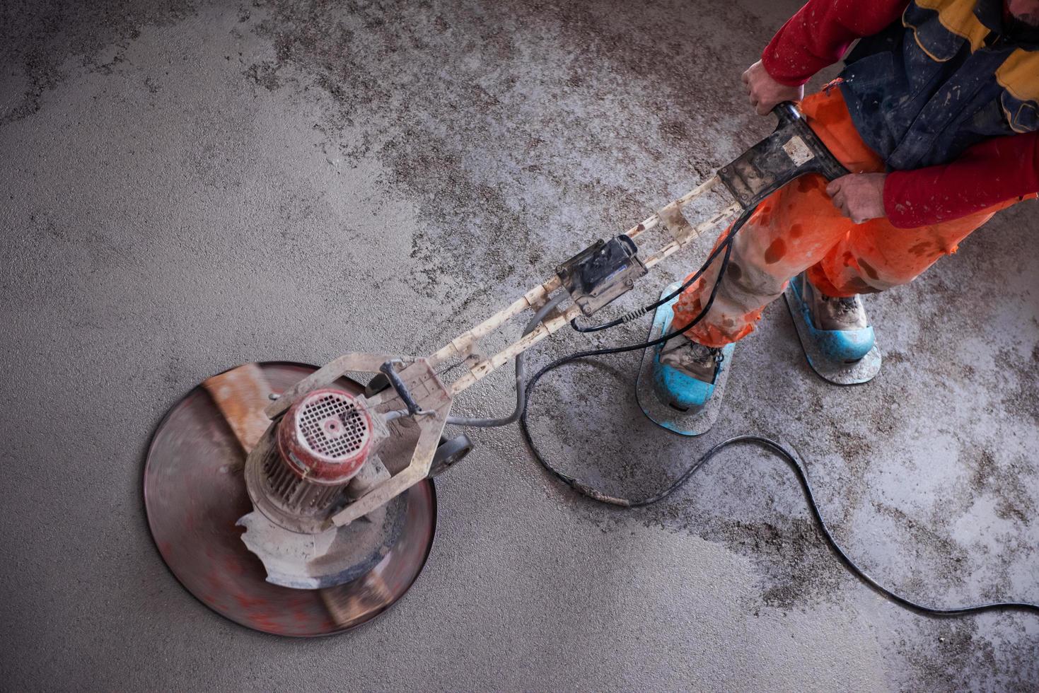 worker performing and polishing sand and cement screed floor photo