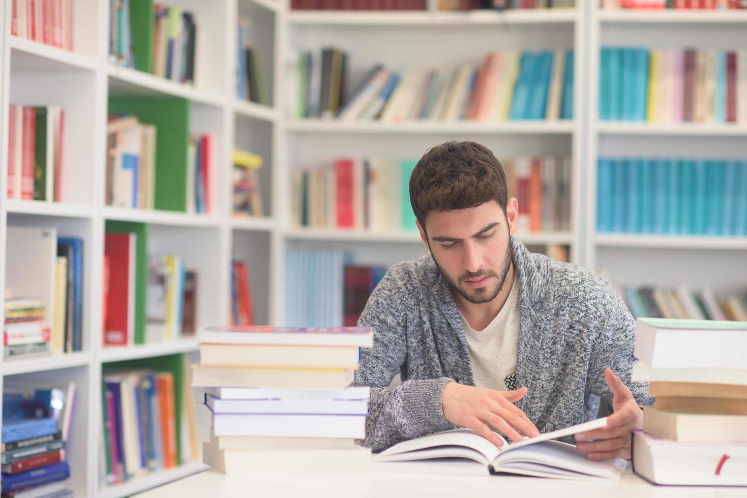 portrait of student while reading book  in school library photo