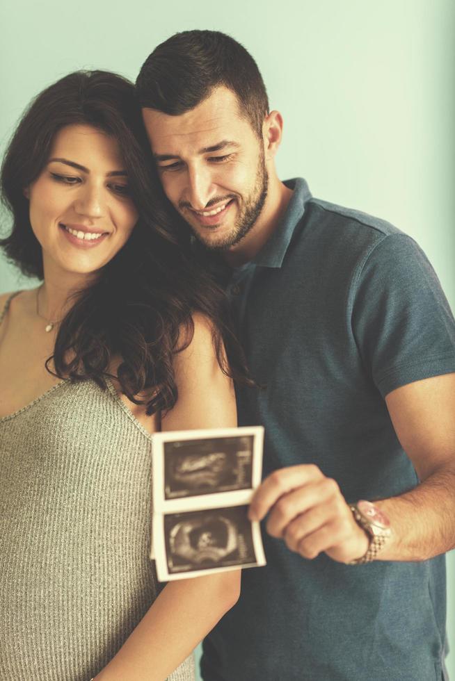 couple looking ultrasound picture isolated on blue background photo