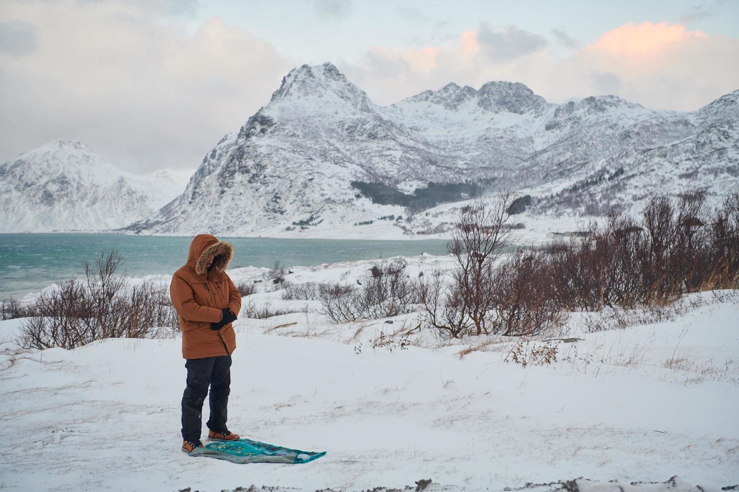 Muslim traveler praying in cold snowy winter day photo