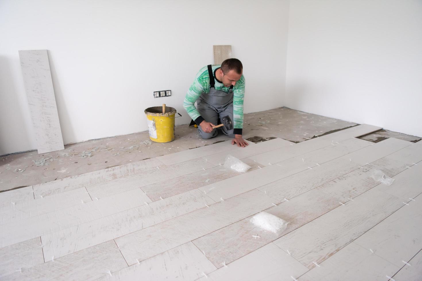 trabajador instalando las baldosas cerámicas con efecto madera en el suelo foto