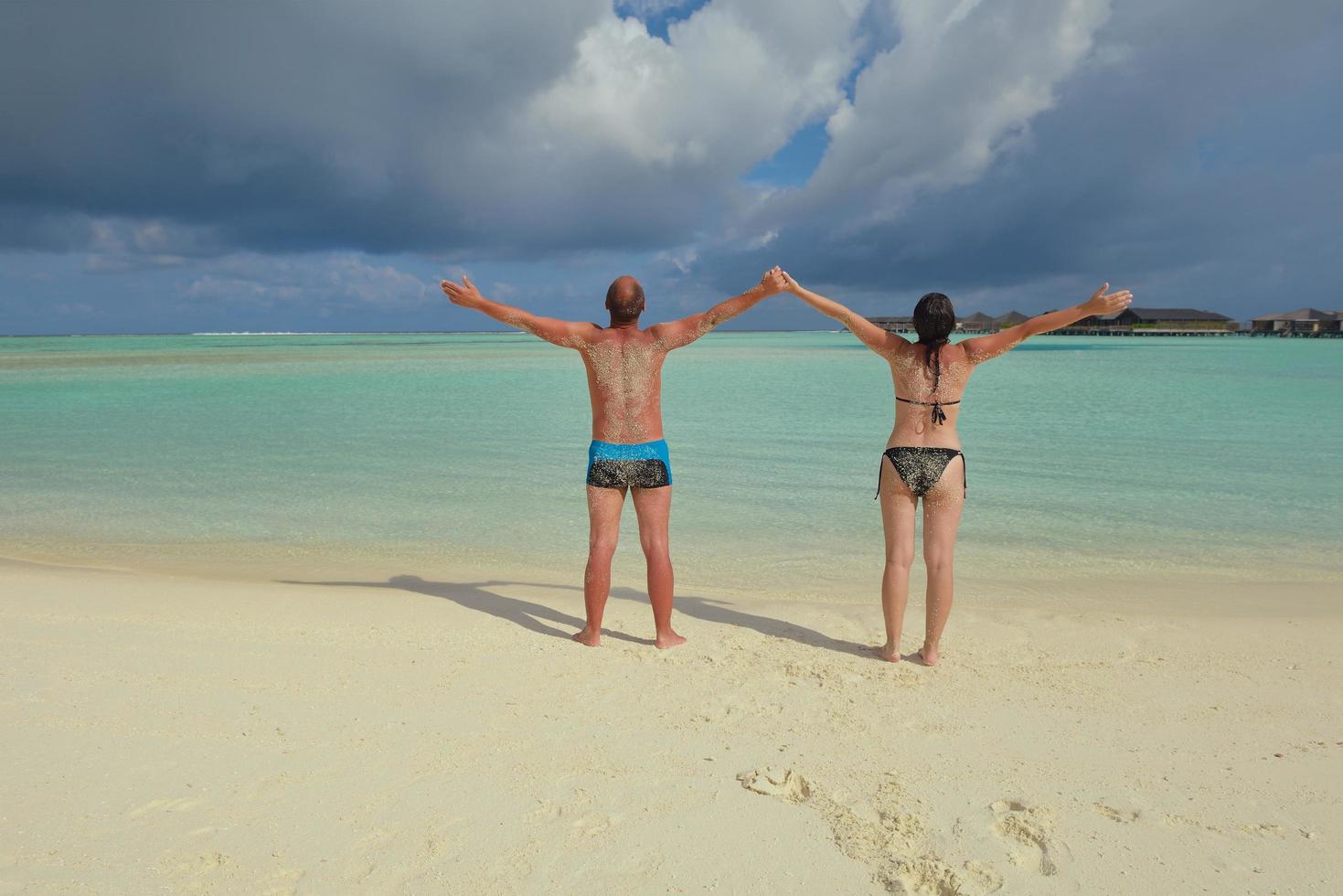 feliz pareja joven divertirse en la playa foto