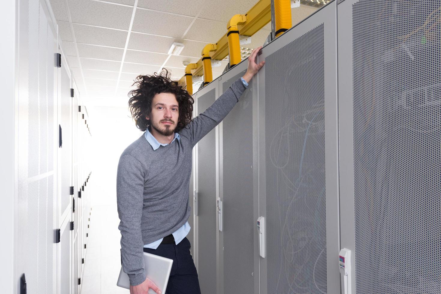 IT engineer working on a tablet computer in server room photo