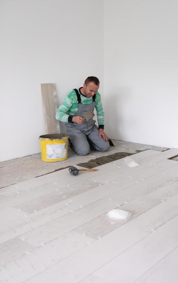 trabajador instalando las baldosas cerámicas con efecto madera en el suelo foto