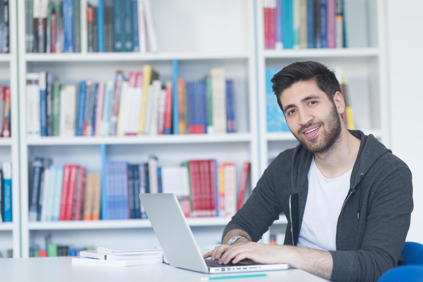 student in school library using laptop for research photo