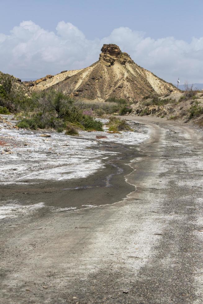 dirt track in the desert with mountain in the background photo