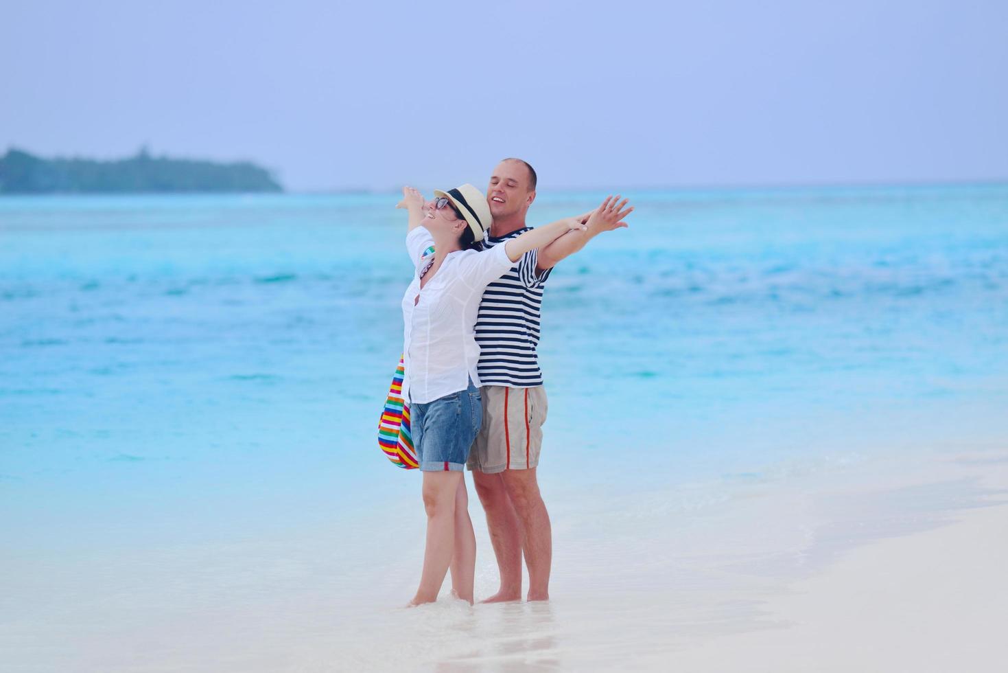 feliz pareja joven divertirse en la playa foto