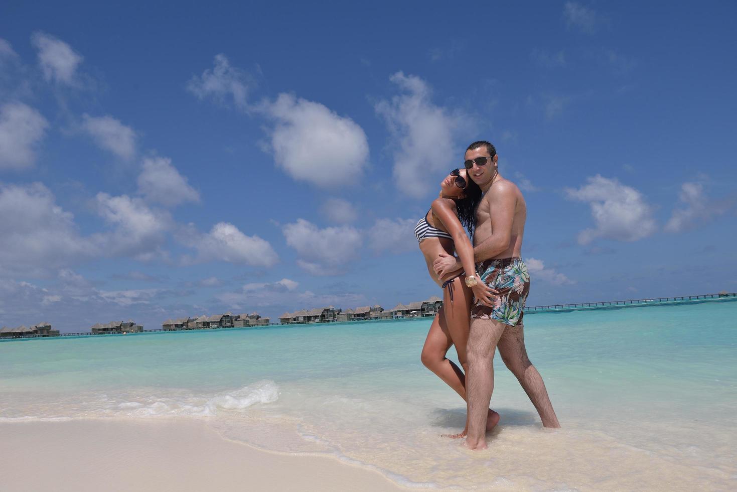 feliz pareja joven divertirse en la playa foto