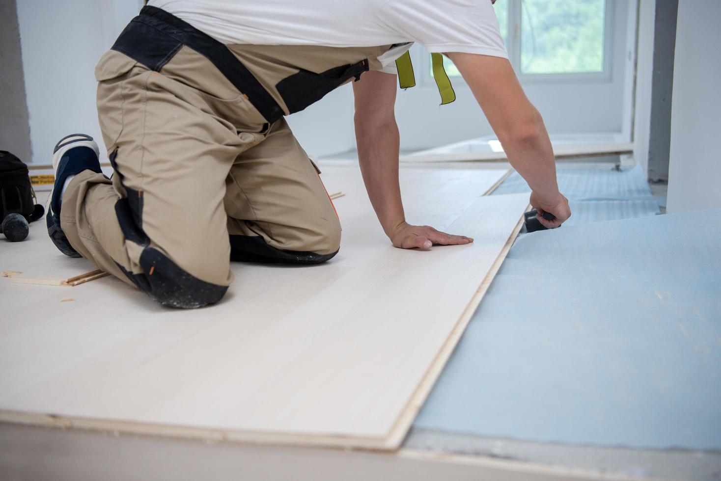 trabajador profesional instalando un nuevo piso de madera laminada foto