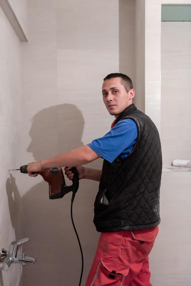 construction worker drilling holes in the bathroom photo