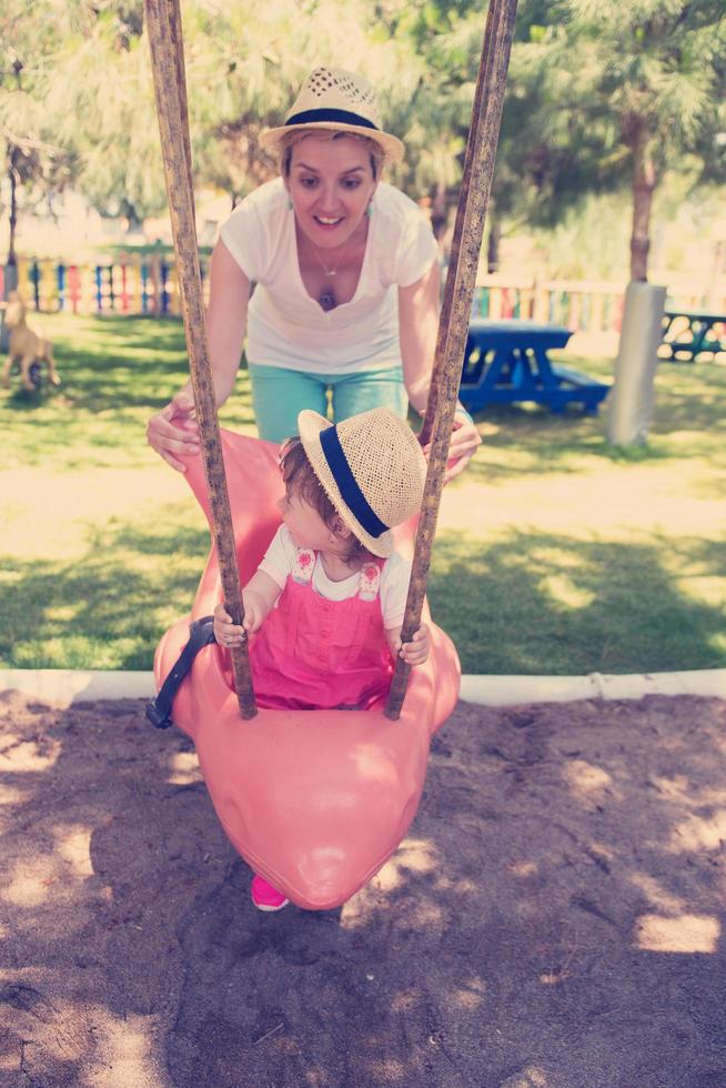 mother and daughter swinging in the park photo