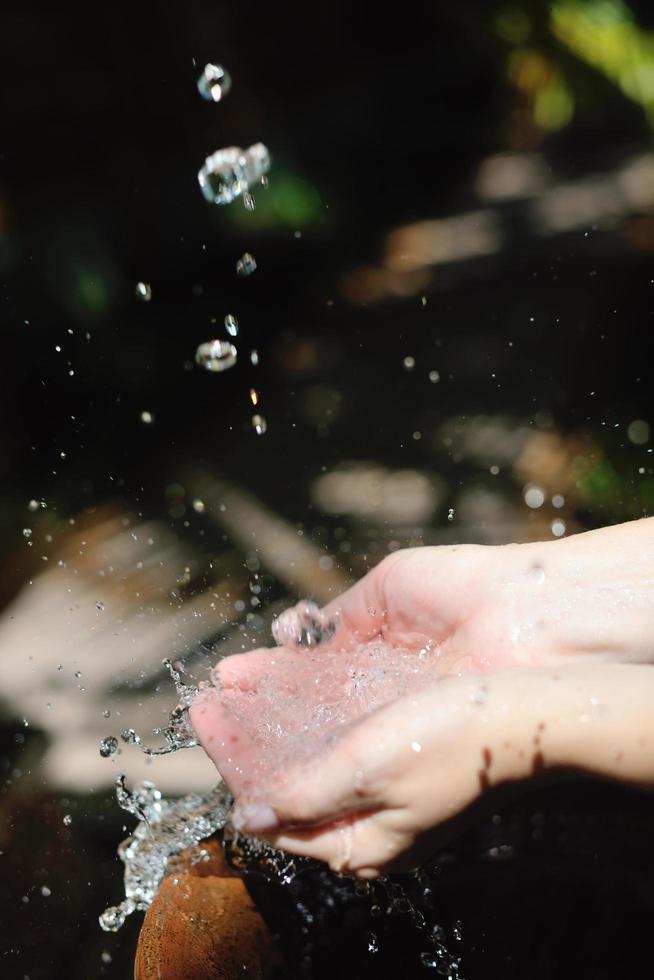 salpicando agua dulce en manos de mujer foto