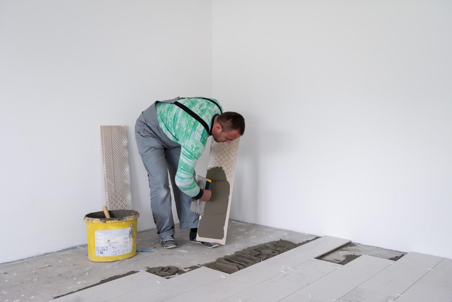 worker installing the ceramic wood effect tiles on the floor photo