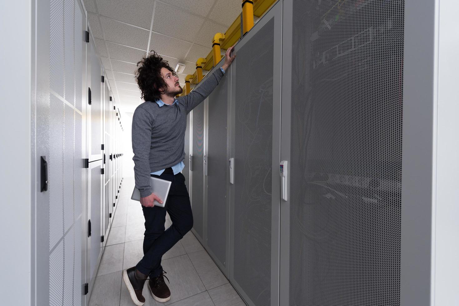 IT engineer working on a tablet computer in server room photo