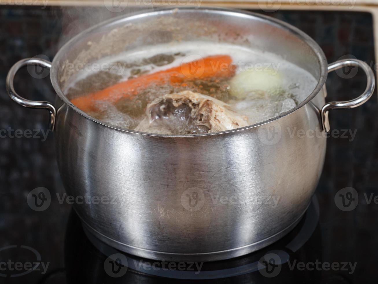 simmering chicken soup in pot on cooker close up photo