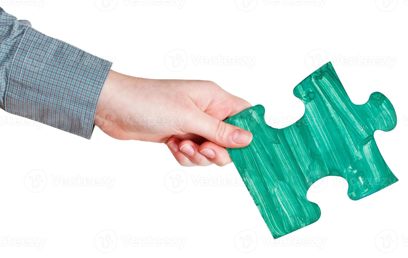 female hand with painted green puzzle piece photo