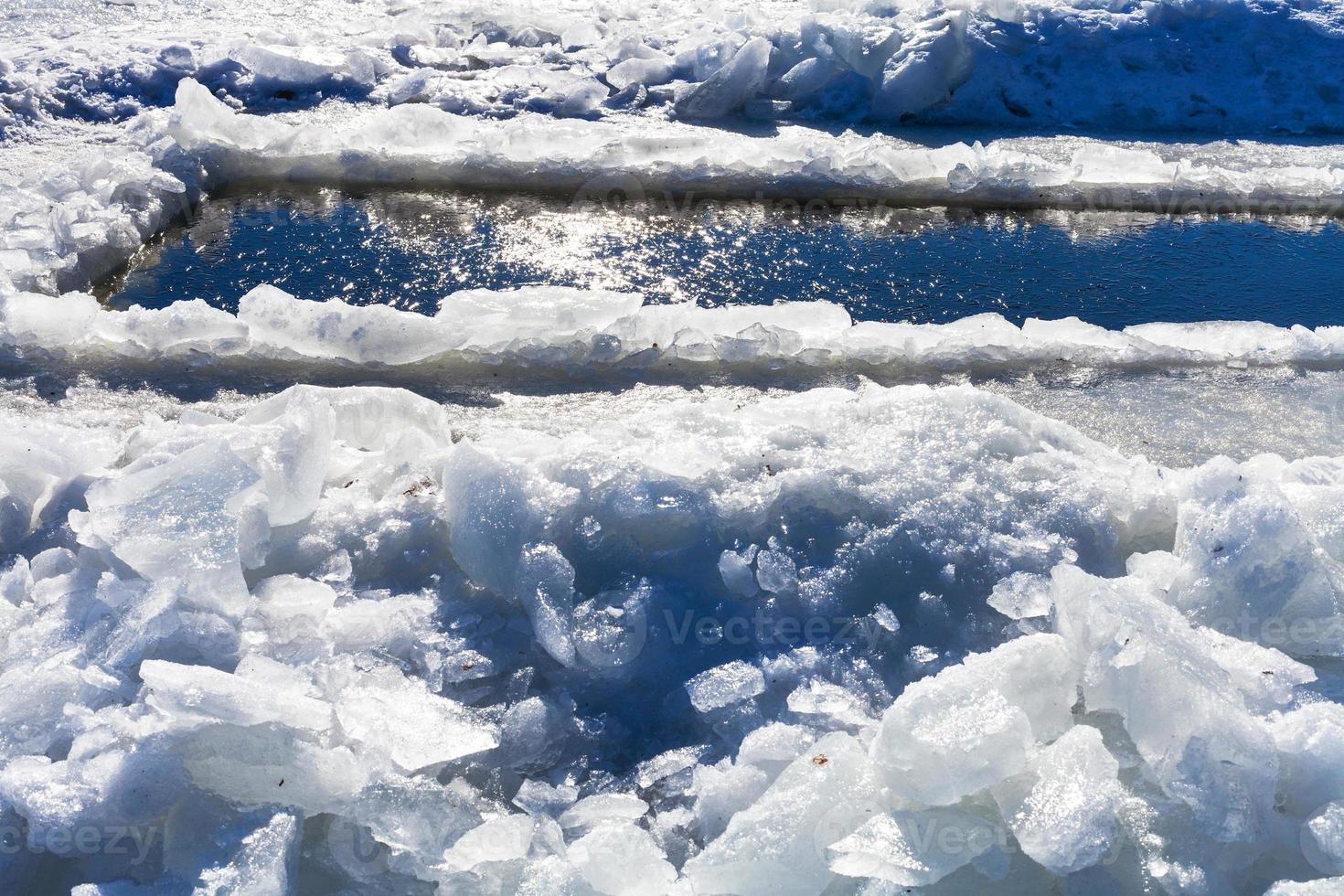 broken ice blocks and ice-hole in frozen rive photo