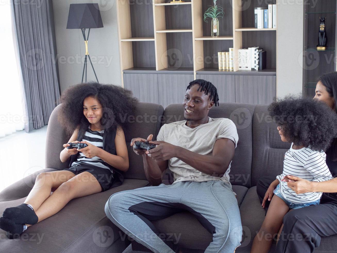 Family father mother child son girl kid female male parent black skin african playing game video controller joystick parent happy relax lifestyle funny holiday vacation living room home house sofa photo