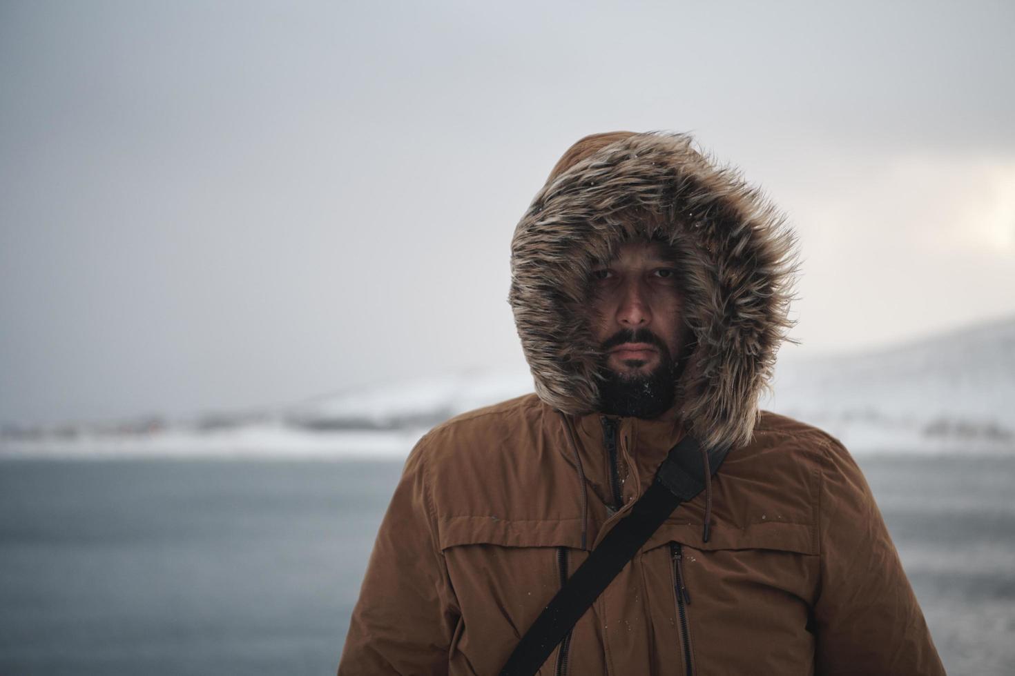 man at winter in stormy weather wearing warm  fur jacket photo