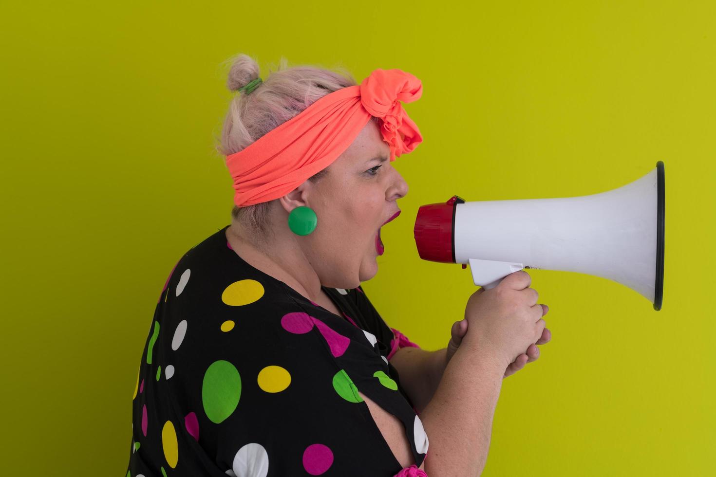 Funny plus size woman woman posing isolated on pastel green background studio portrait. People emotions lifestyle concept. Mock up copy space. Screaming in megaphone. photo