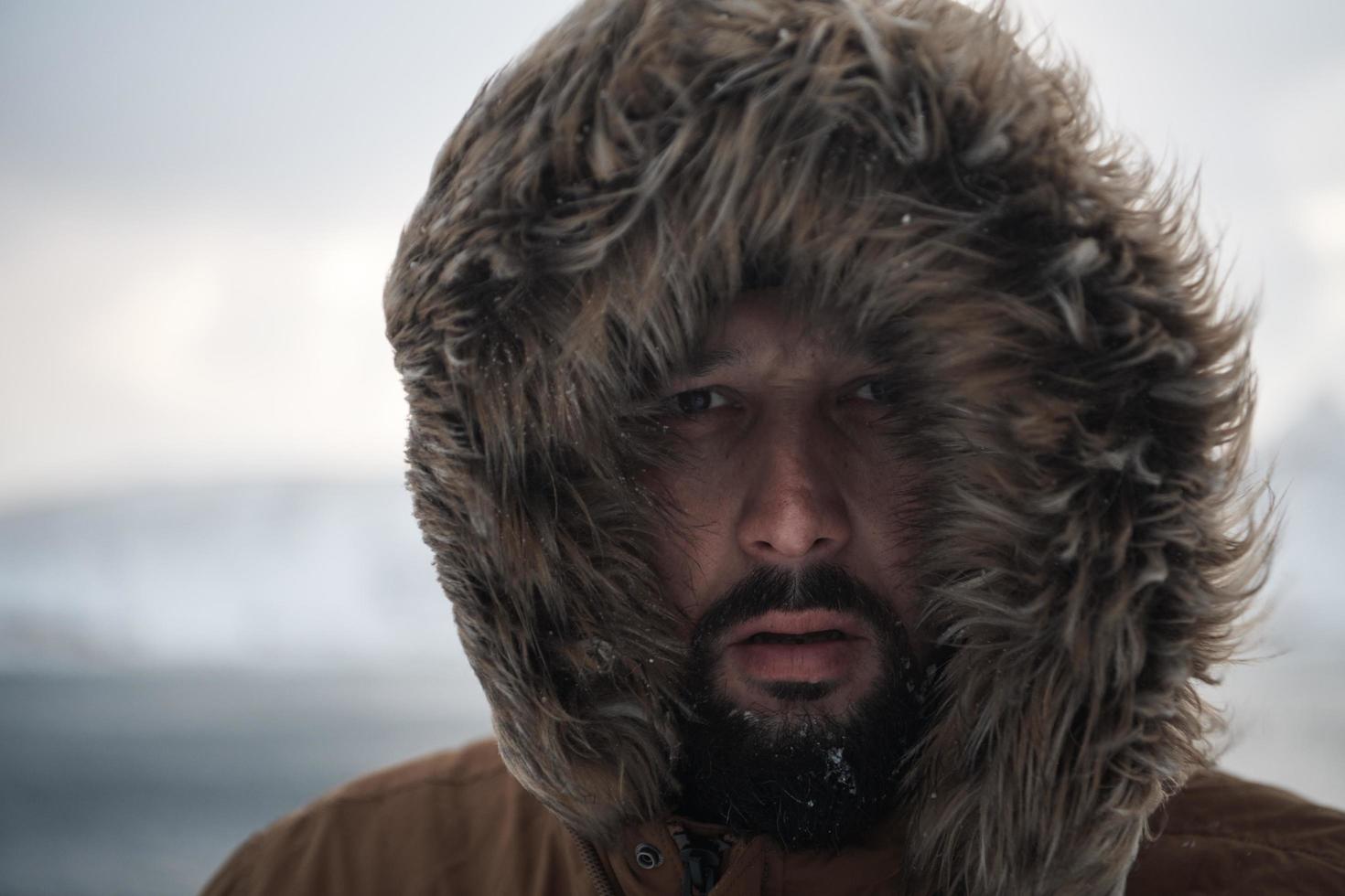 man at winter in stormy weather wearing warm  fur jacket photo