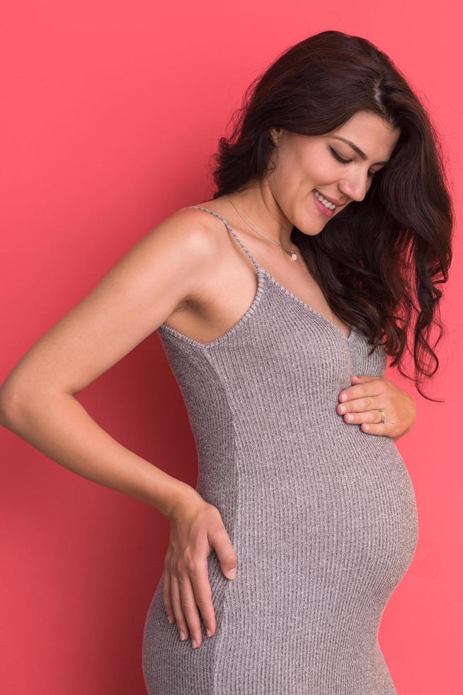 Portrait of pregnant woman over red background photo