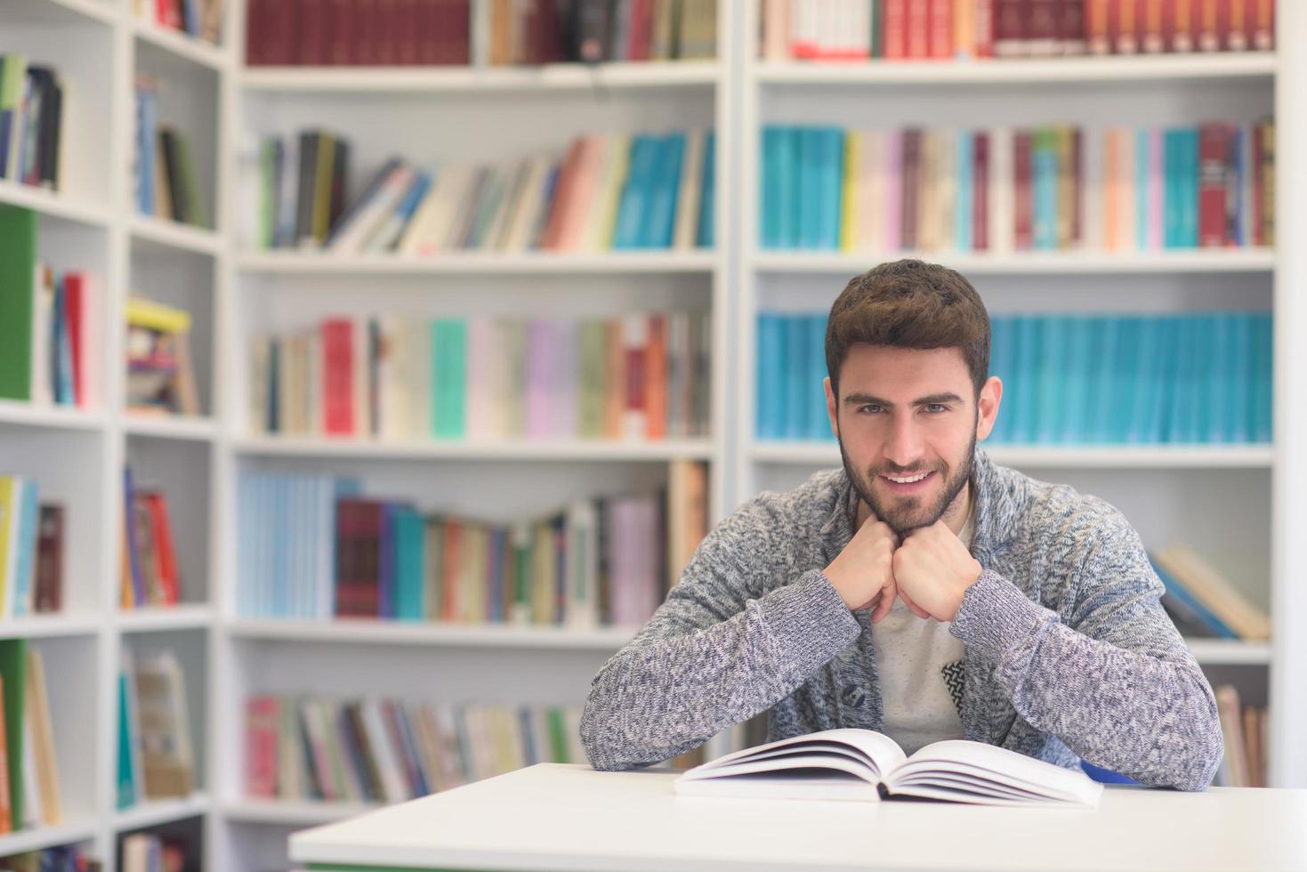 portrait of student while reading book  in school library photo