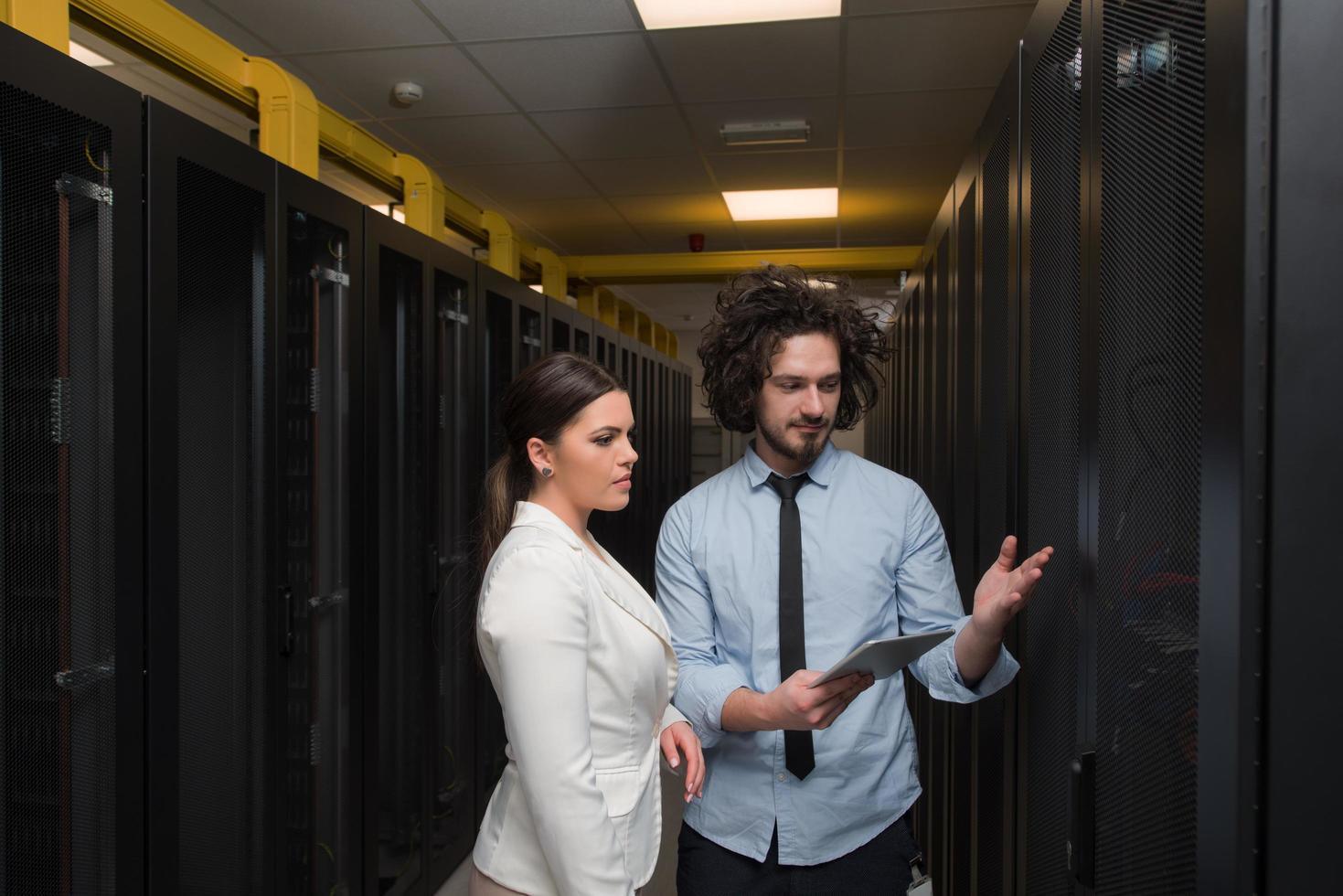 engineer showing working data center server room to female chief photo