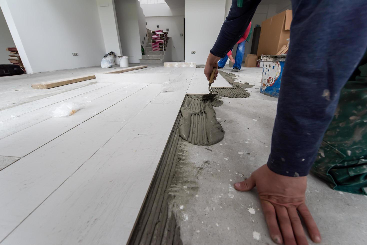 worker installing the ceramic wood effect tiles on the floor photo