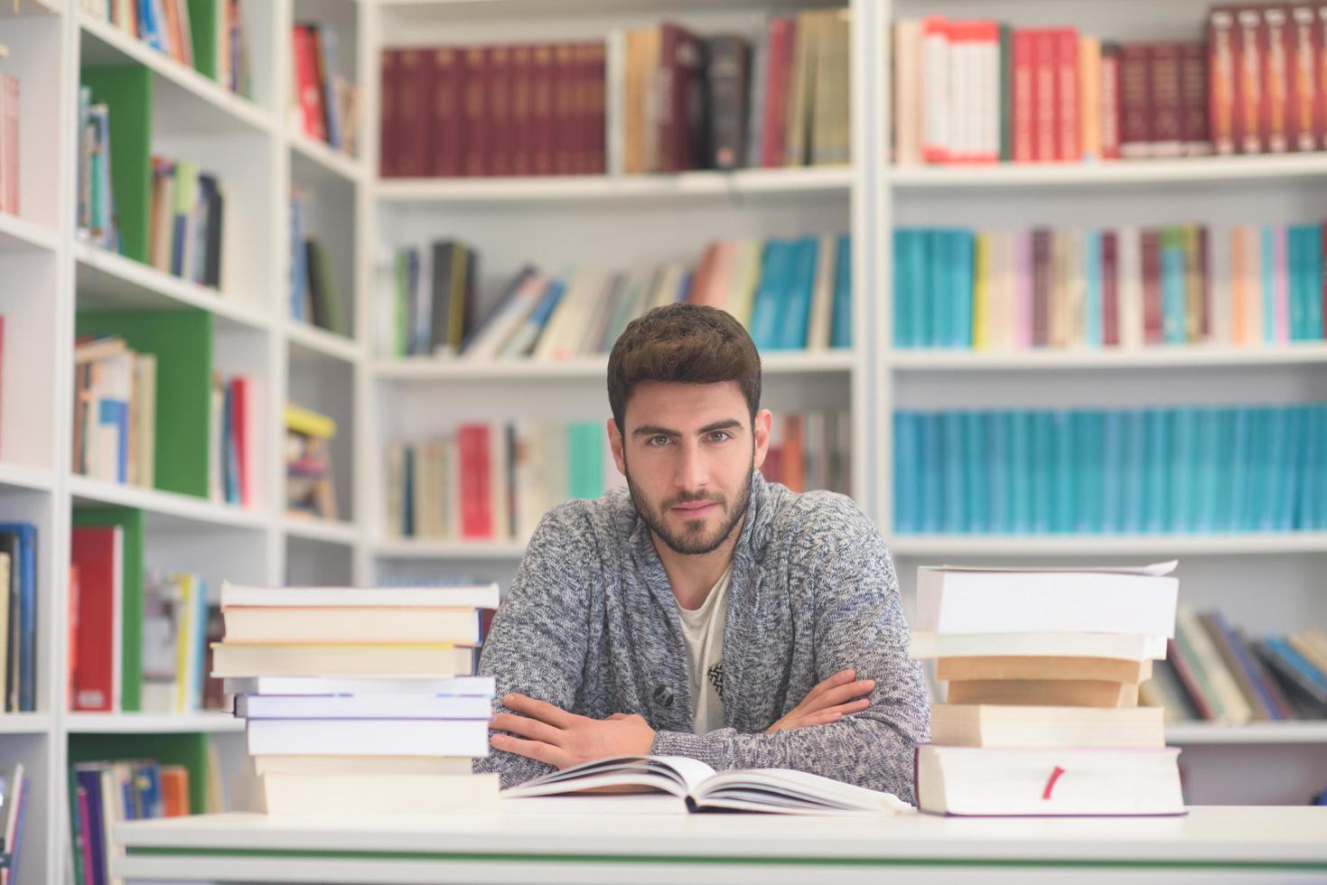 portrait of student while reading book  in school library photo