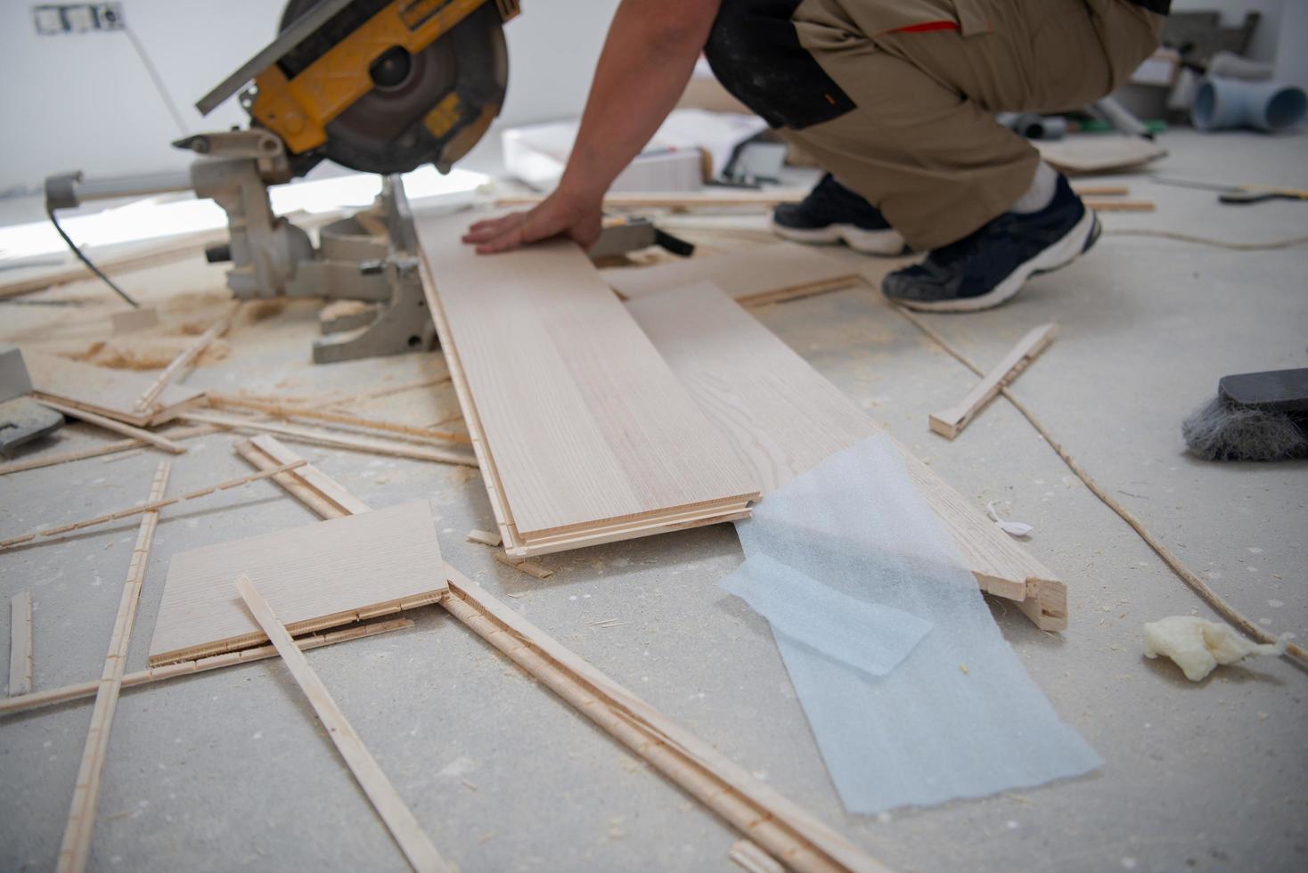 Man cutting laminate floor plank with electrical circular saw 11926673