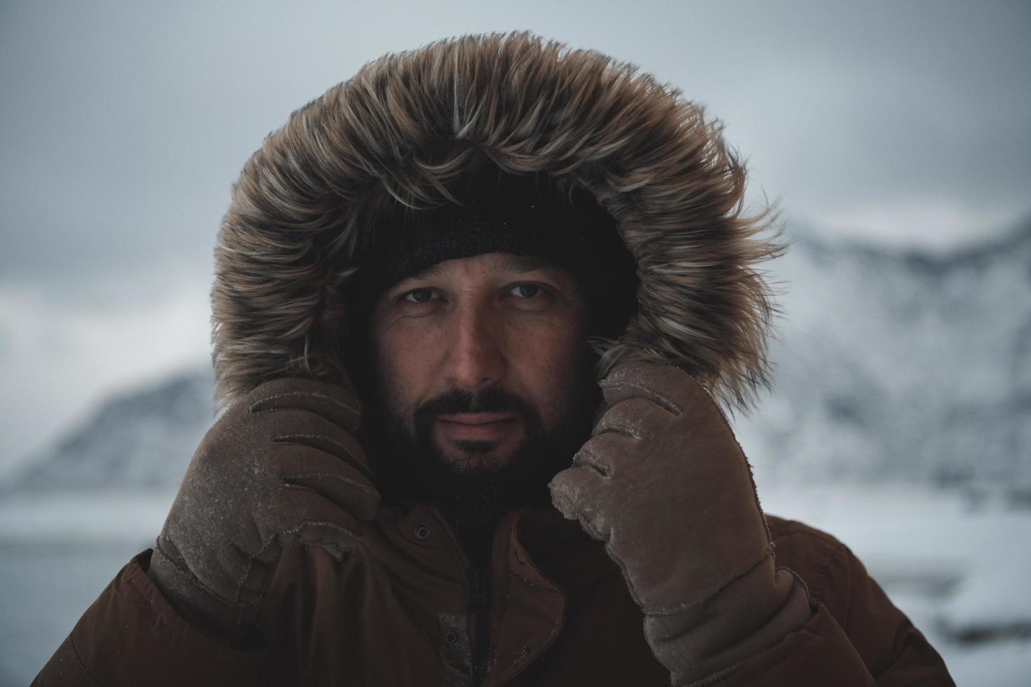 man at winter in stormy weather wearing warm  fur jacket photo