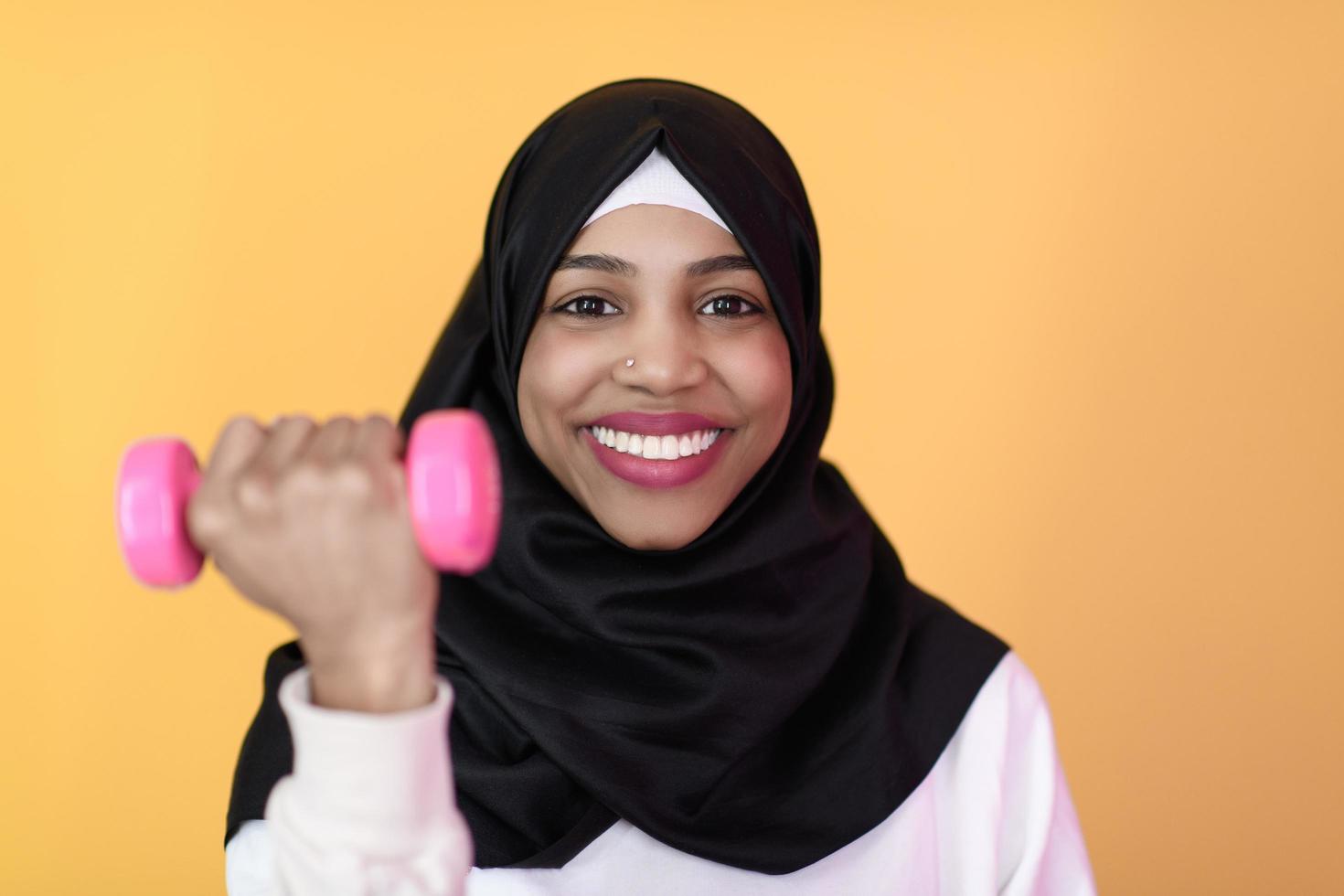 afro muslim woman promotes a healthy life, holding dumbbells in her hands photo