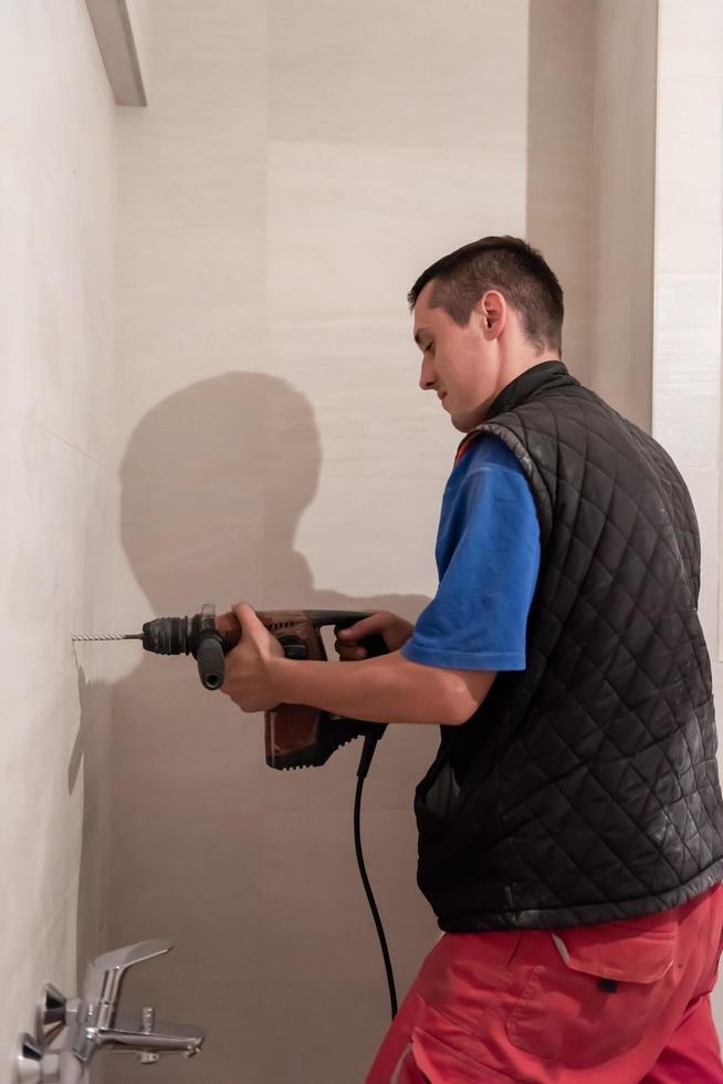 construction worker drilling holes in the bathroom photo