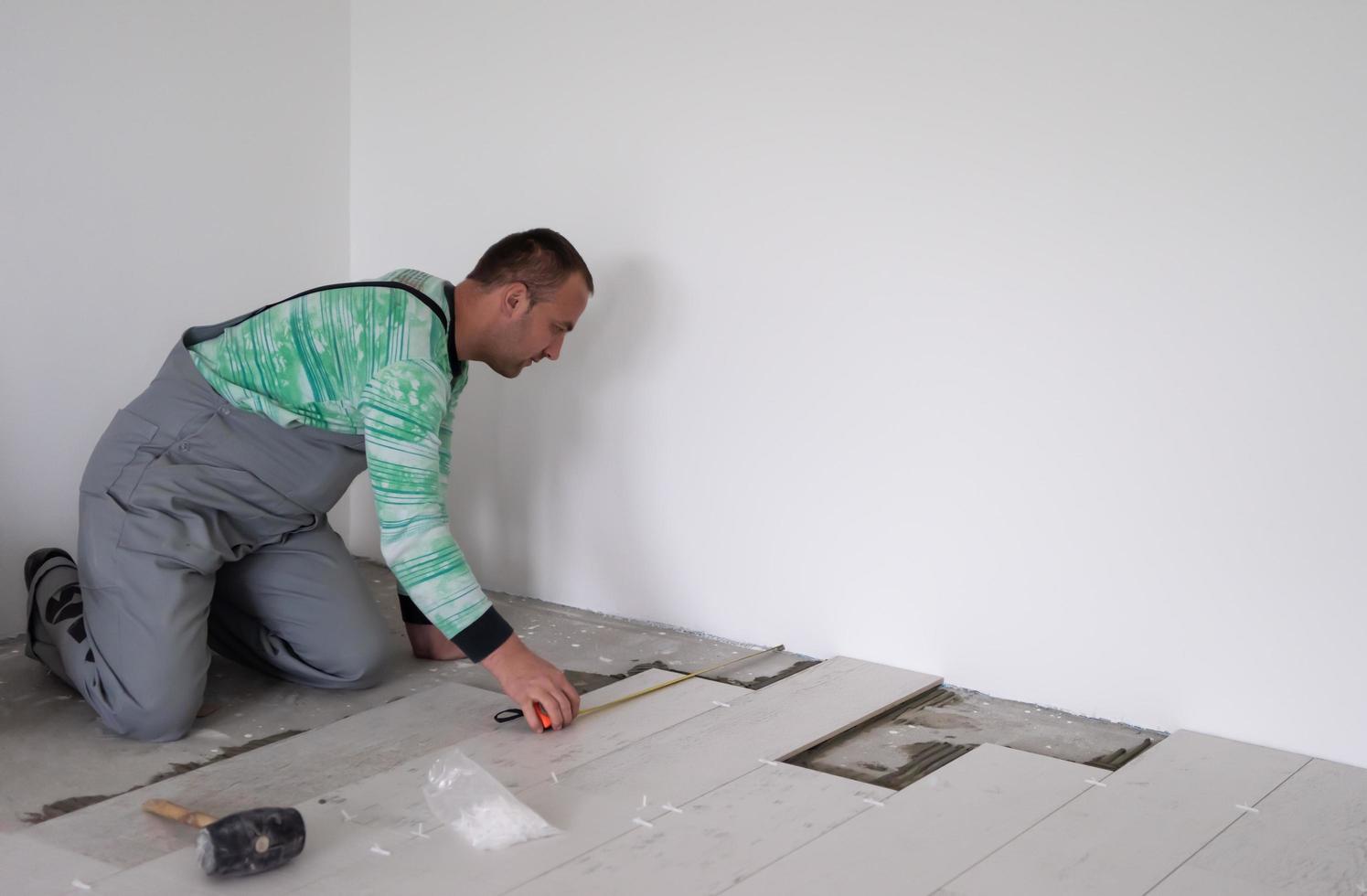 worker installing the ceramic wood effect tiles on the floor photo