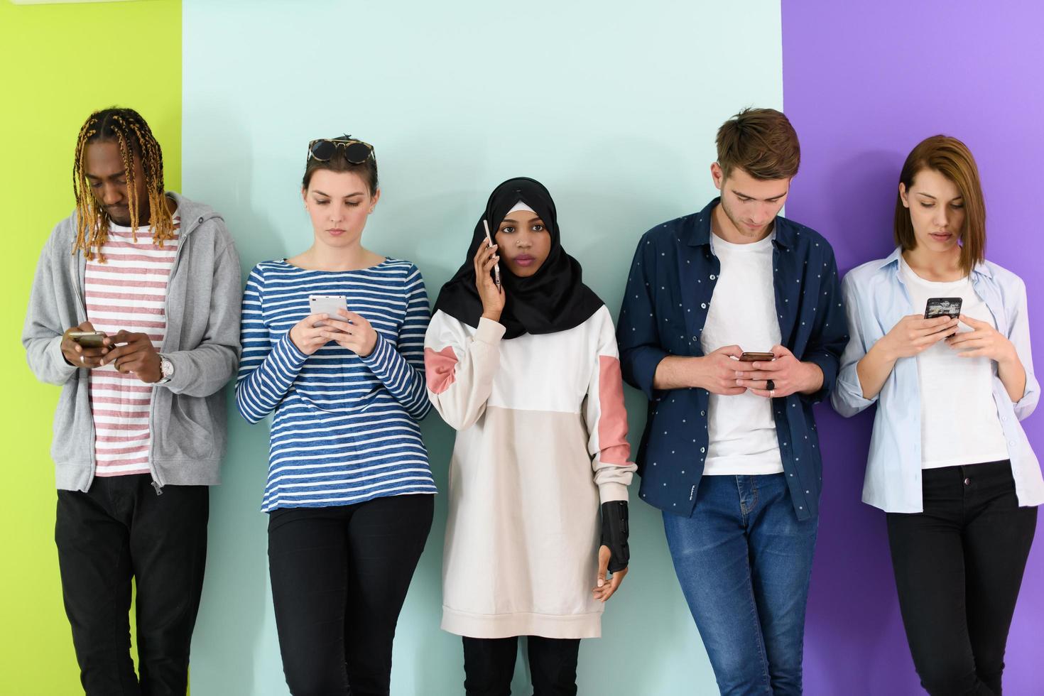 diverse teenagers use mobile devices while posing for studio photography photo